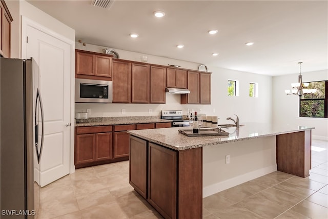 kitchen with an inviting chandelier, a kitchen island with sink, light stone countertops, stainless steel appliances, and decorative light fixtures