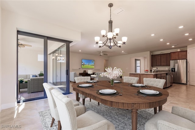 dining space featuring light tile patterned flooring, sink, and ceiling fan with notable chandelier