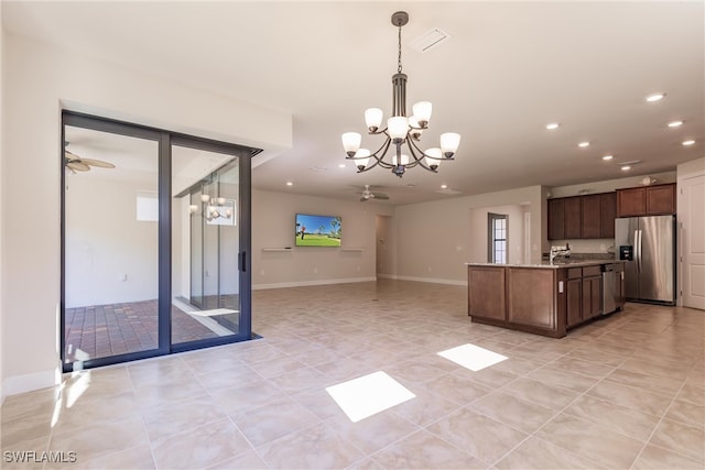 kitchen featuring hanging light fixtures, appliances with stainless steel finishes, light stone countertops, ceiling fan with notable chandelier, and sink