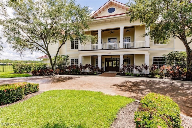 neoclassical home with covered porch, a balcony, and a front lawn