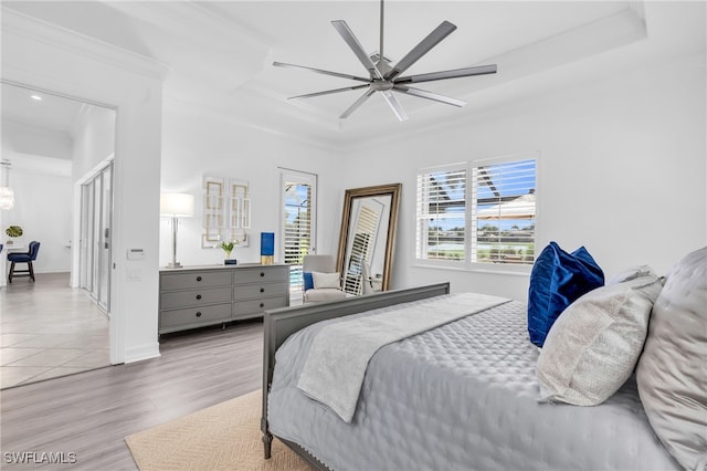 bedroom with a raised ceiling, ceiling fan, crown molding, and light hardwood / wood-style flooring