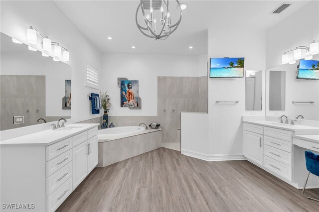 bathroom with wood-type flooring, vanity, shower with separate bathtub, and an inviting chandelier