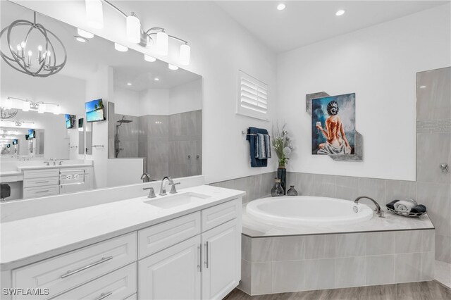 bathroom with vanity, wood-type flooring, a notable chandelier, and shower with separate bathtub