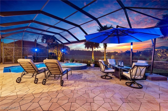 patio terrace at dusk featuring a lanai and a pool with hot tub