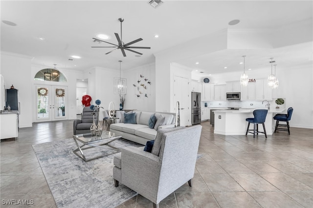 tiled living room with crown molding, french doors, and ceiling fan with notable chandelier