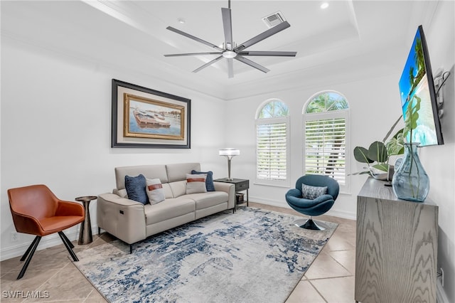 tiled living room featuring a raised ceiling, ceiling fan, and ornamental molding