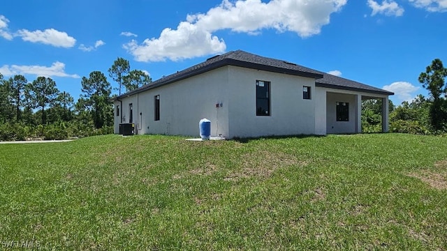 rear view of property featuring central air condition unit and a lawn