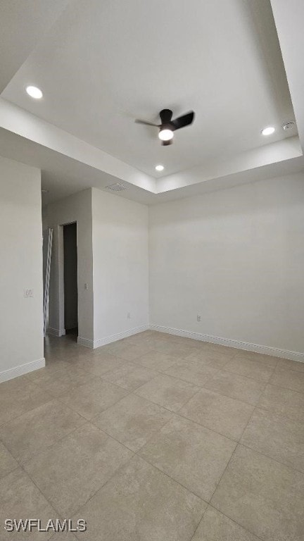 unfurnished room with ceiling fan and a tray ceiling