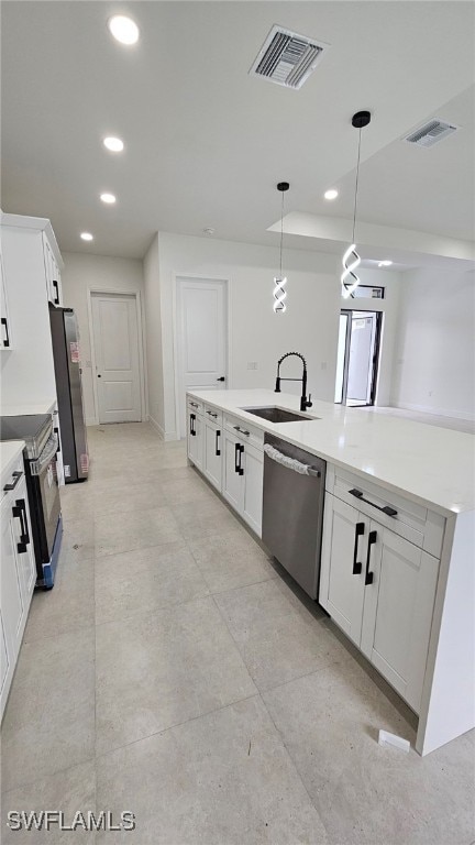 kitchen with appliances with stainless steel finishes, white cabinets, decorative light fixtures, and sink