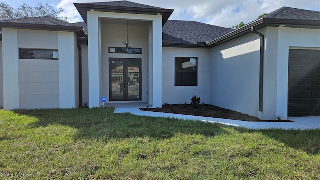 view of exterior entry featuring a garage, french doors, and a yard