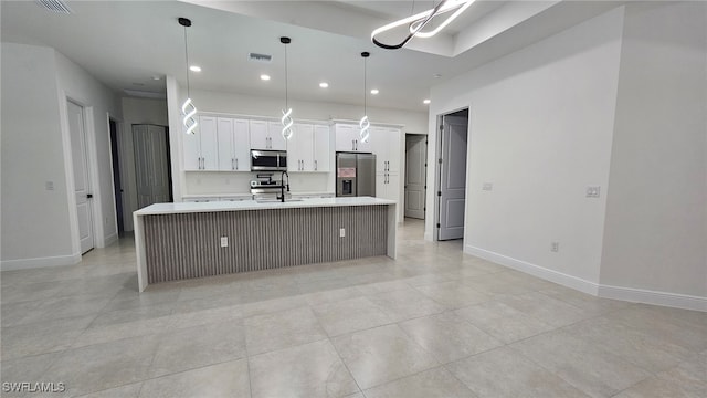 kitchen with appliances with stainless steel finishes, hanging light fixtures, an island with sink, light tile patterned floors, and white cabinets