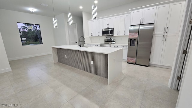 kitchen with sink, white cabinets, an island with sink, pendant lighting, and appliances with stainless steel finishes