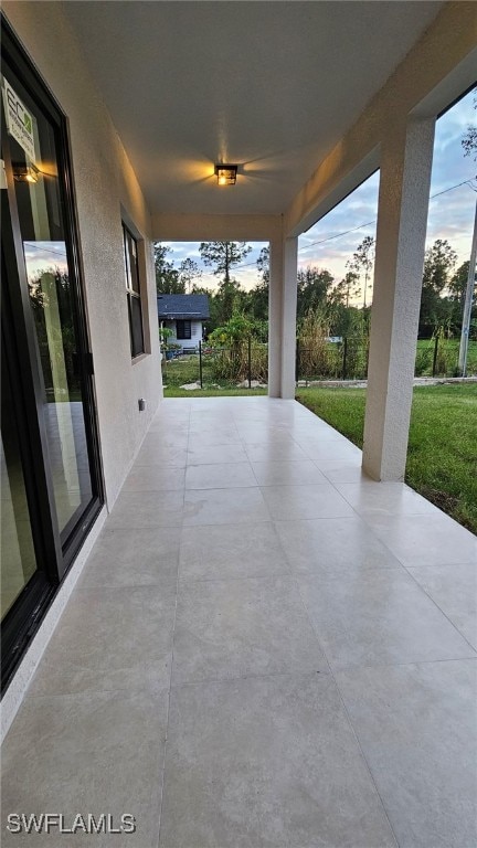 patio terrace at dusk featuring ceiling fan and a yard