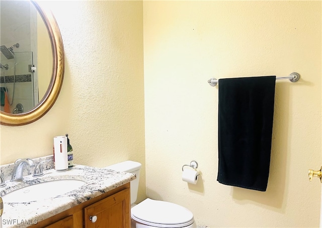 bathroom featuring vanity, a shower with shower door, and toilet