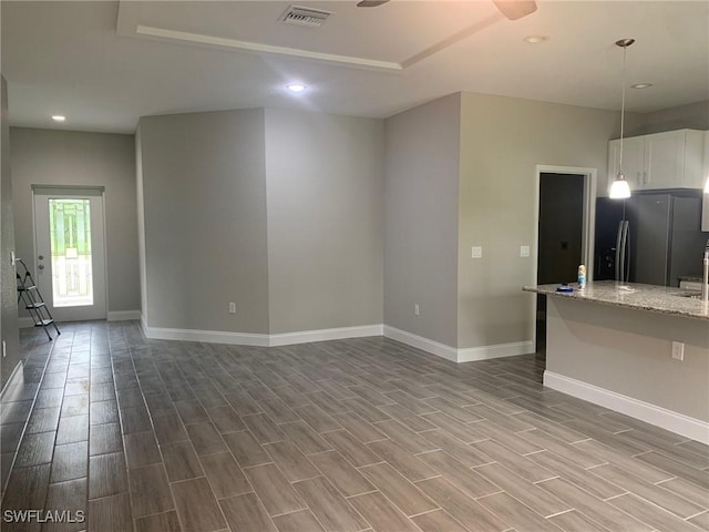 unfurnished living room featuring wood finish floors, visible vents, baseboards, and recessed lighting