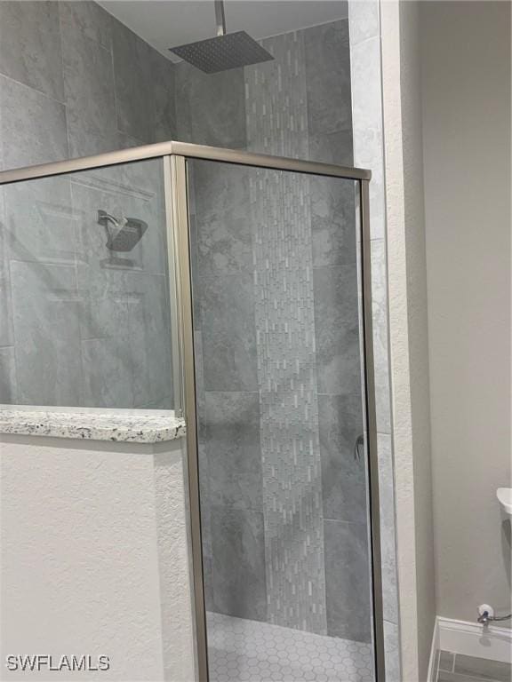 bathroom with baseboards and a stall shower