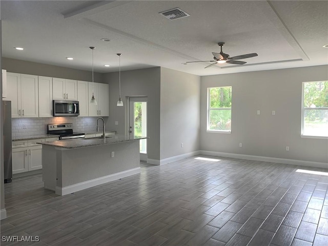 kitchen with visible vents, a sink, open floor plan, stainless steel appliances, and decorative backsplash