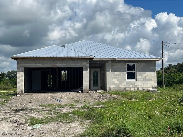 property in mid-construction featuring metal roof and concrete block siding