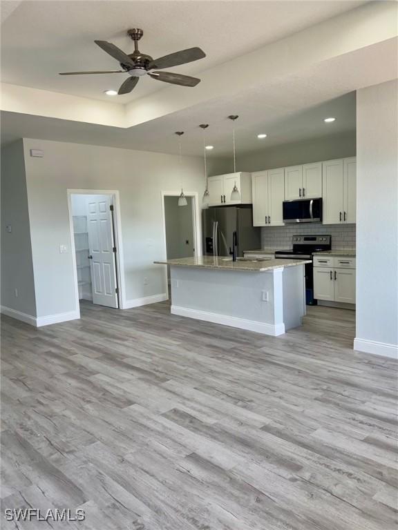 2001 Jeronimo Rd, Labelle, FL 33935 - kitchen featuring stainless steel appliances, light wood finished floors, baseboards, a ceiling fan, and white cabinetry