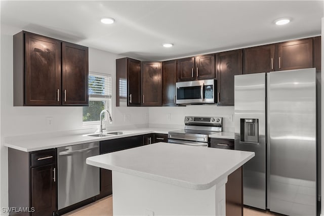 kitchen with appliances with stainless steel finishes, light tile patterned floors, a center island, dark brown cabinetry, and sink