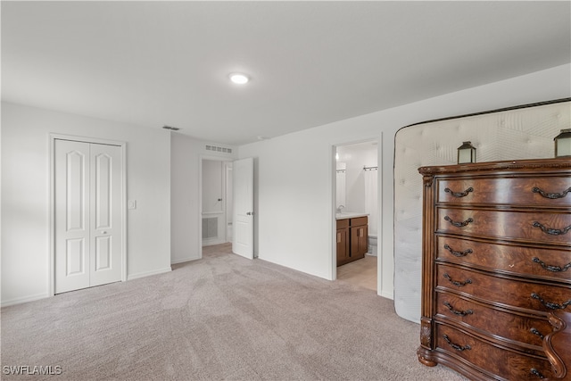 unfurnished bedroom with a closet, light colored carpet, and ensuite bathroom