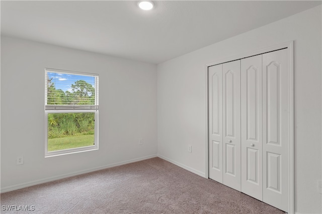 unfurnished bedroom with light carpet and a closet