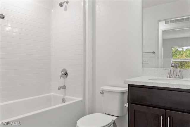 full bathroom featuring tiled shower / bath, vanity, and toilet