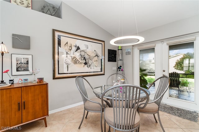 dining space with french doors, lofted ceiling, and light tile patterned flooring