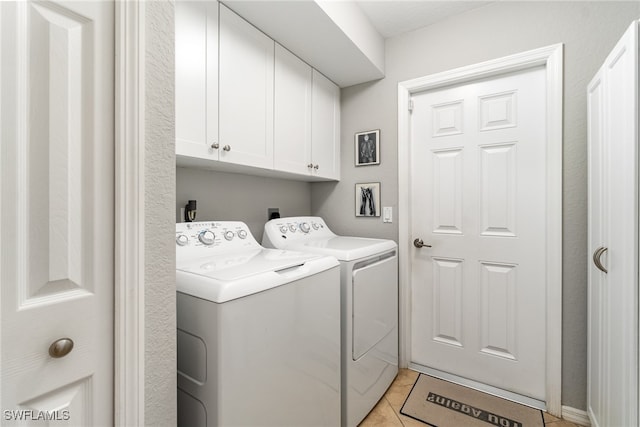 clothes washing area featuring cabinets, washing machine and dryer, and light tile patterned flooring