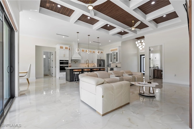 living room featuring ceiling fan with notable chandelier, coffered ceiling, and beam ceiling