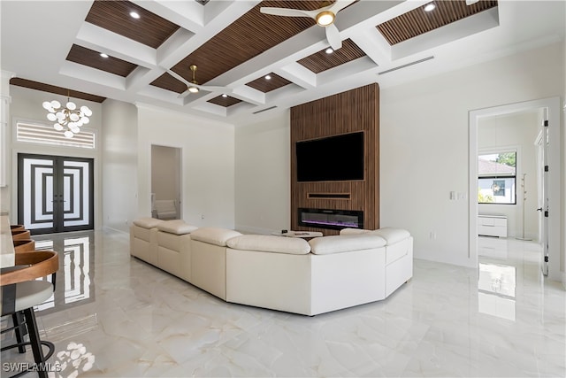 living room with ceiling fan with notable chandelier, a fireplace, coffered ceiling, and beamed ceiling