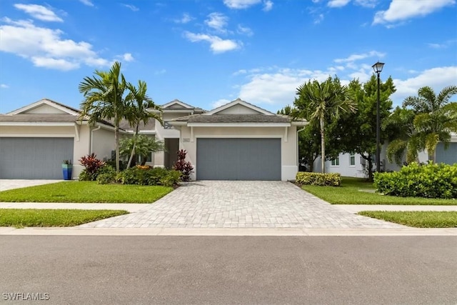 ranch-style home with decorative driveway, a front yard, an attached garage, and stucco siding