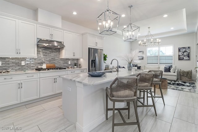 kitchen with white cabinets, sink, stainless steel appliances, and a kitchen island with sink