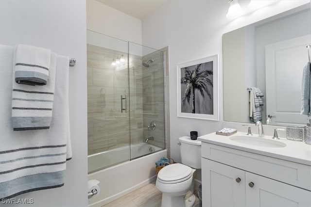 full bathroom featuring hardwood / wood-style floors, vanity, bath / shower combo with glass door, and toilet