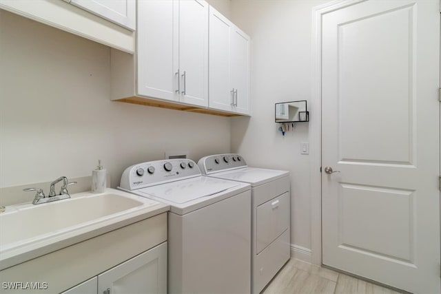 clothes washing area with washing machine and clothes dryer, sink, and cabinets