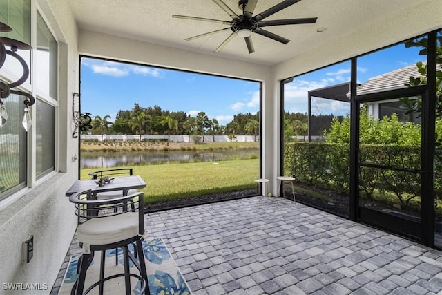 sunroom featuring ceiling fan and a water view