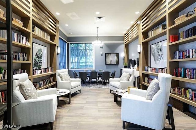 living area with crown molding and light hardwood / wood-style flooring