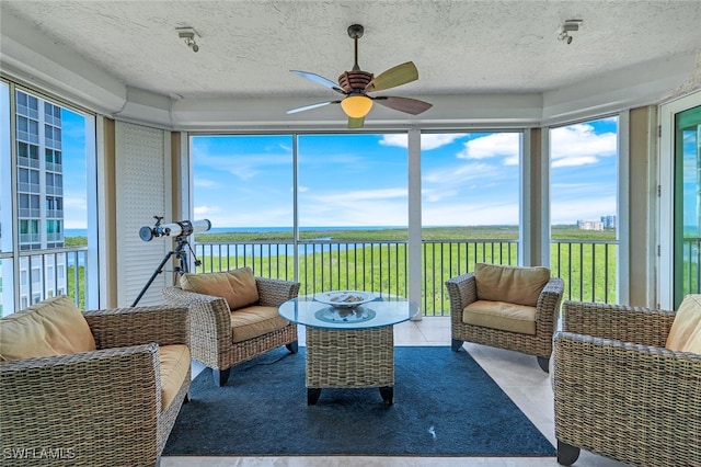 sunroom / solarium with a healthy amount of sunlight, a water view, and ceiling fan