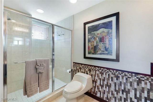full bathroom featuring a stall shower, toilet, recessed lighting, tile walls, and wainscoting