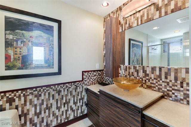 full bath featuring wainscoting, tile walls, vanity, visible vents, and a stall shower