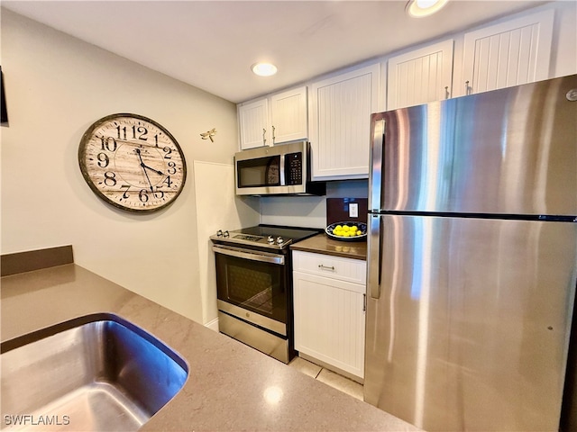 kitchen featuring appliances with stainless steel finishes, white cabinetry, and sink