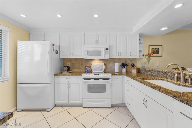 kitchen with dark stone counters, crown molding, white appliances, sink, and white cabinets