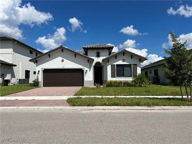 mediterranean / spanish house featuring a garage, central AC unit, and a front yard