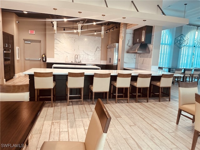 kitchen with pendant lighting, a breakfast bar area, light hardwood / wood-style floors, and a towering ceiling