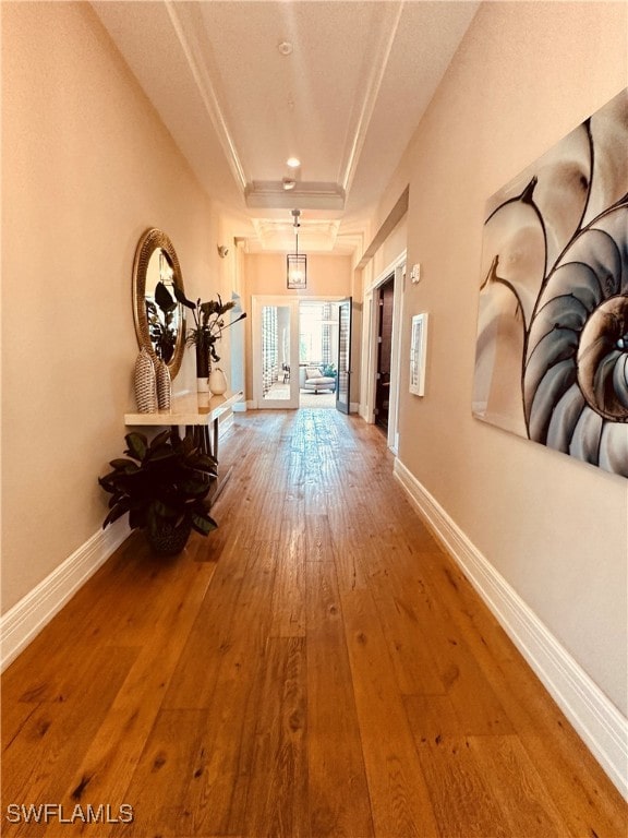 corridor with french doors, hardwood / wood-style floors, and a tray ceiling