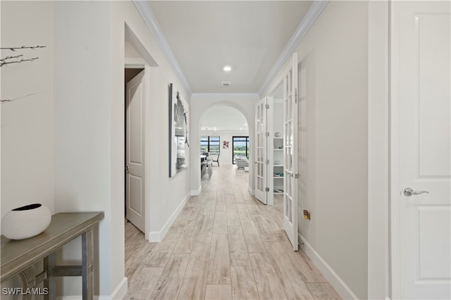 hall featuring ornamental molding, light wood-type flooring, and french doors