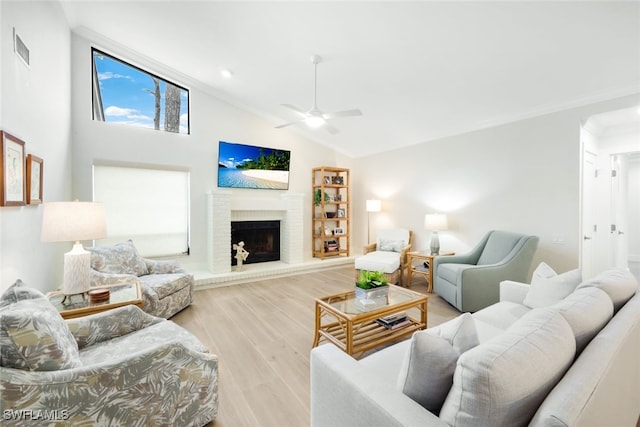 living area featuring light wood-style flooring, a fireplace, visible vents, and crown molding