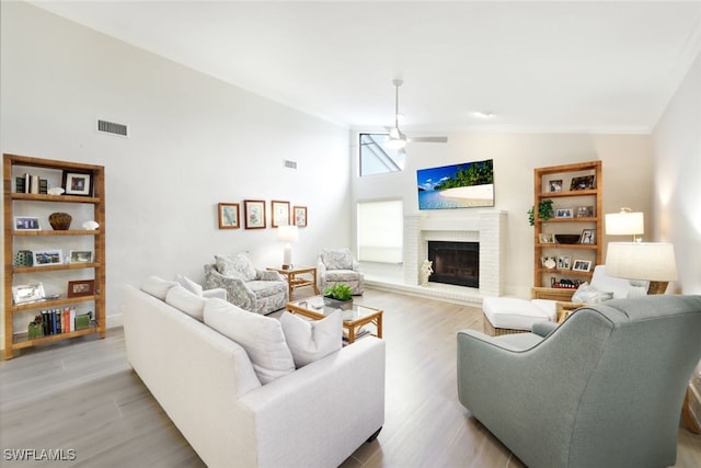 living area with a brick fireplace, visible vents, and light wood-style floors