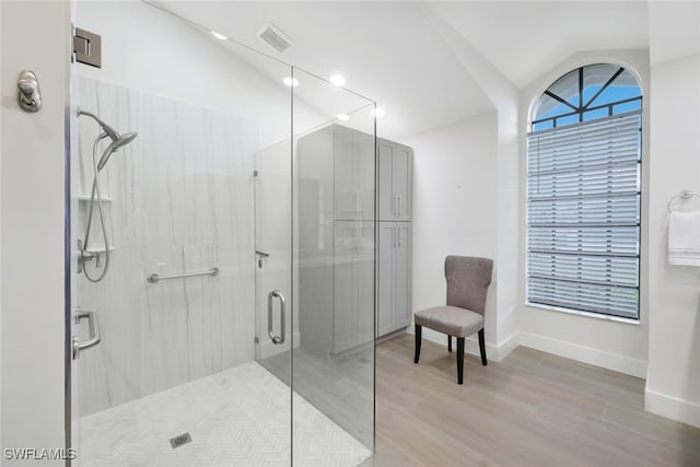 full bathroom featuring lofted ceiling, wood finished floors, visible vents, baseboards, and a shower stall