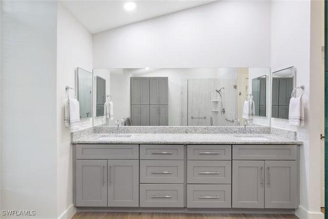 full bathroom with double vanity, a stall shower, and a sink